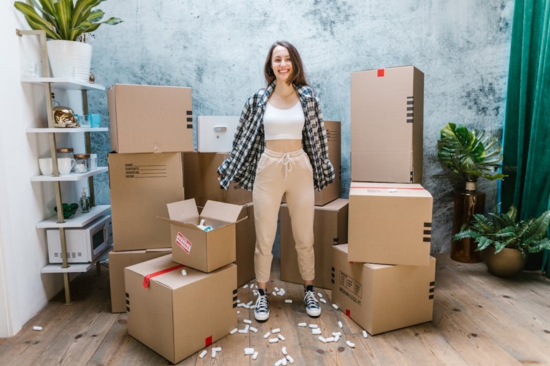 A girl standing near cardboard boxes and smiling.